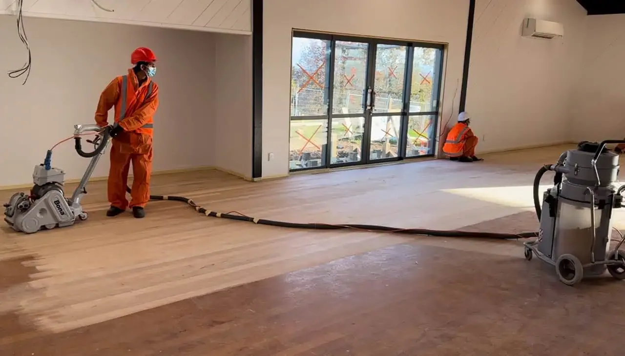 FlooringPro technician operating professional floor sanding equipment on a timber floor